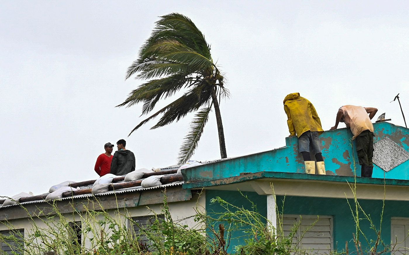 Cubanos reparan un techo en San Juan y Martínez, provincia de Pinar del Río, el 27 de septiembre de 2022 tras el paso del huracán Ian. (Foto de ADALBERTO ROQUE / AFP)