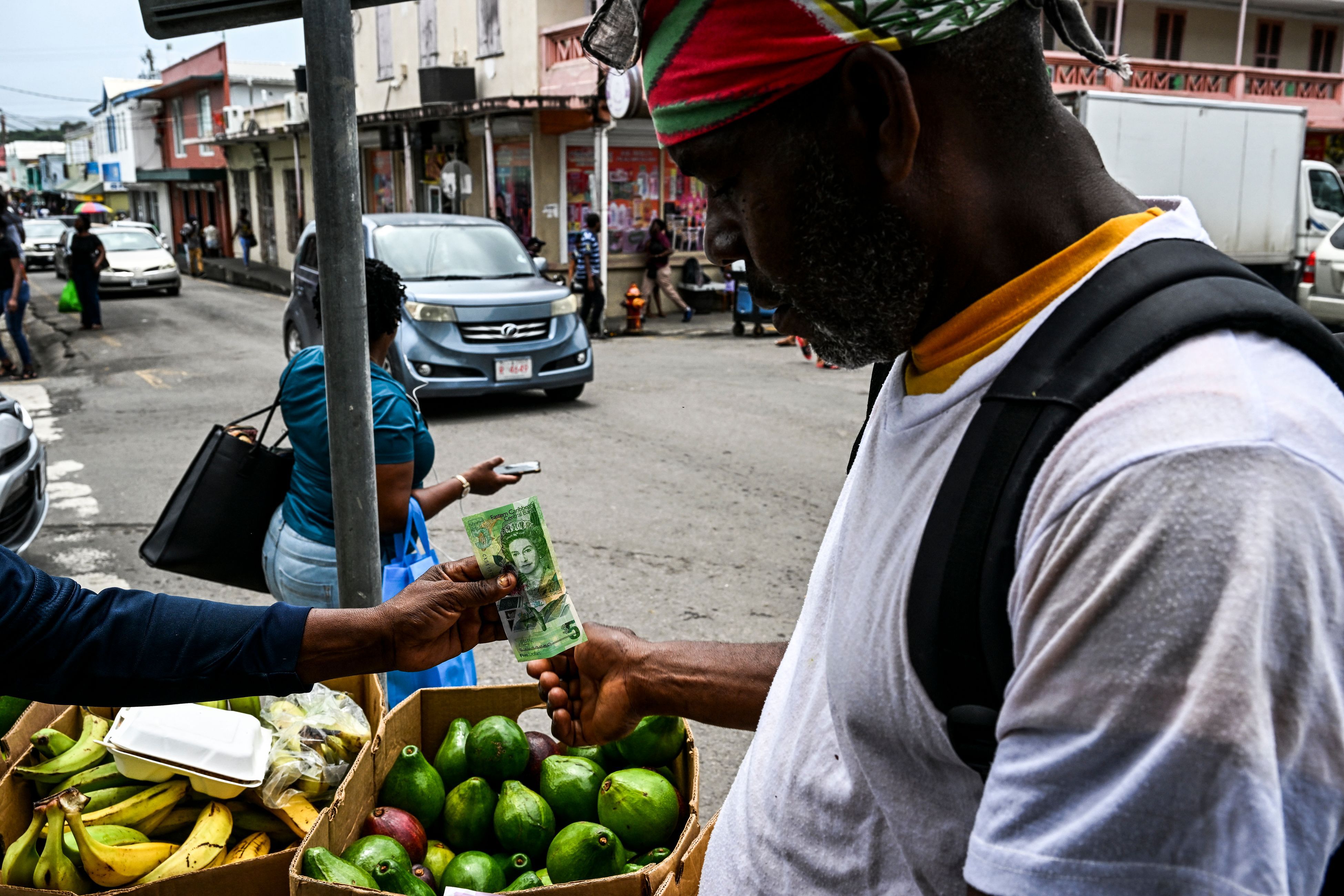 La imagen de la difunta reina Isabel II está plasmada en todos los billetes de Antigua y Barbuda. En la imagen, un hombre la utiliza para comprar fruta en un mercado en la capital, Saint John.