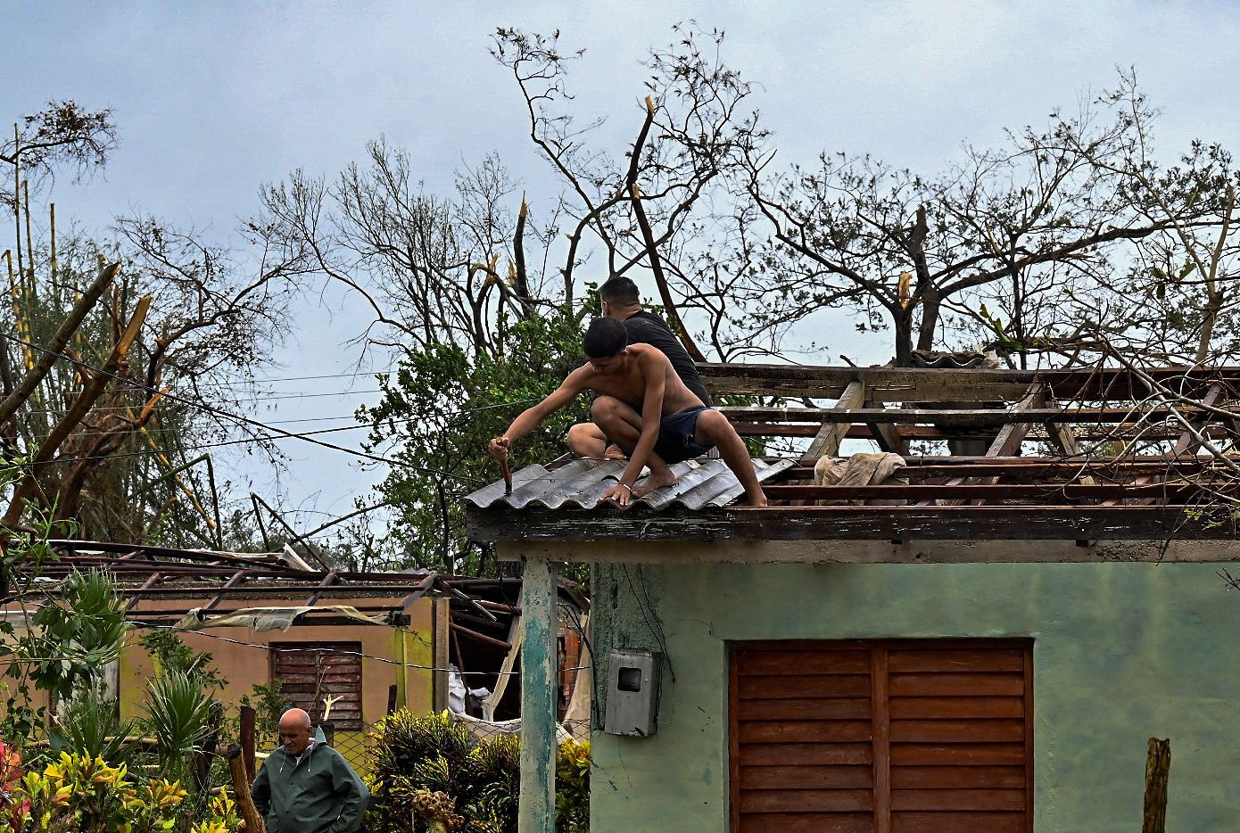 Cubanos reparan un techo en San Juan y Martínez, provincia de Pinar del Río, el 27 de septiembre de 2022 tras el paso del huracán Ian. (Foto de ADALBERTO ROQUE / AFP)