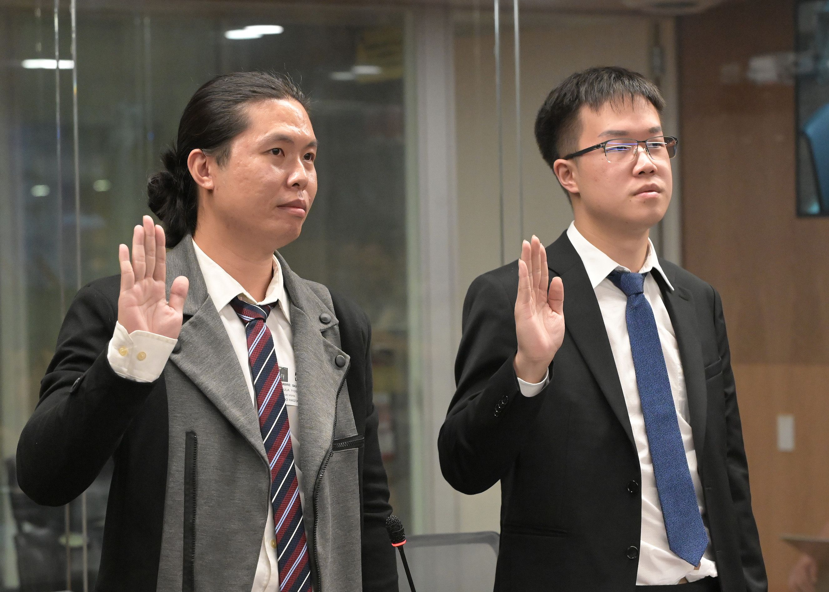 En la imagen se observa la juramentación de De Shen Lin Hu y su traductor personal, previo a comparecer.