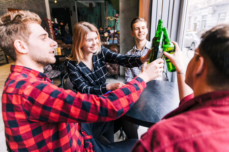 Personas brindando y sonriendo en la mesa de un bar, como símbolo de círculo social, fundamental para reducir el burnout