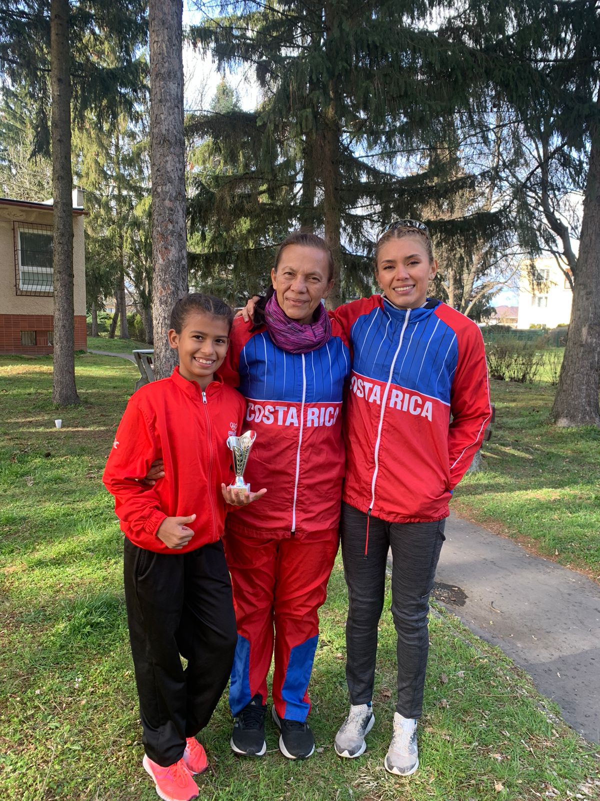 Yara Moya Cortés muestra orgullosa el trofeo que obtuvo al ganar el segundo lugar en Eslovaquia. junto a ella su entrenadora Dixiana Mena y la atleta olímpica Noelia Vargas. Cortesía: Aracelly Cortés
